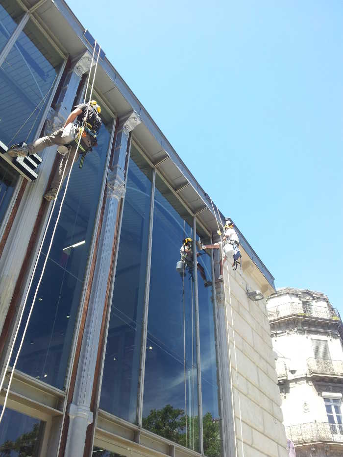 Traitement et mise en peinture de colonnes en faade par des techniciens cordistes